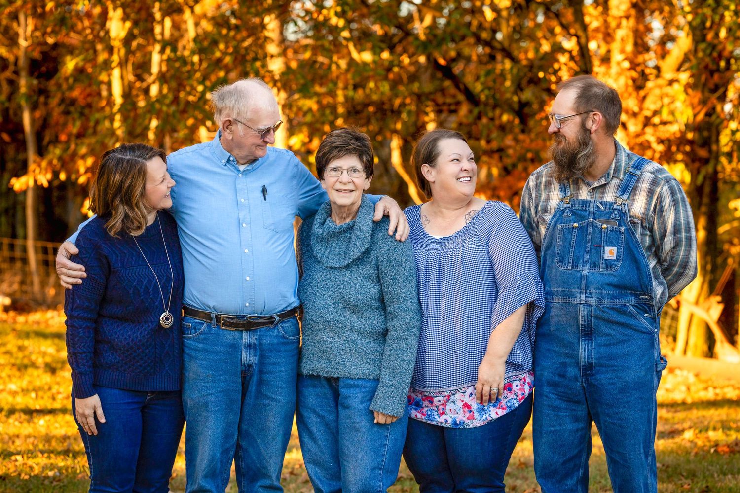 Group portrait of family members sharing laughter together in autumn sunlight.