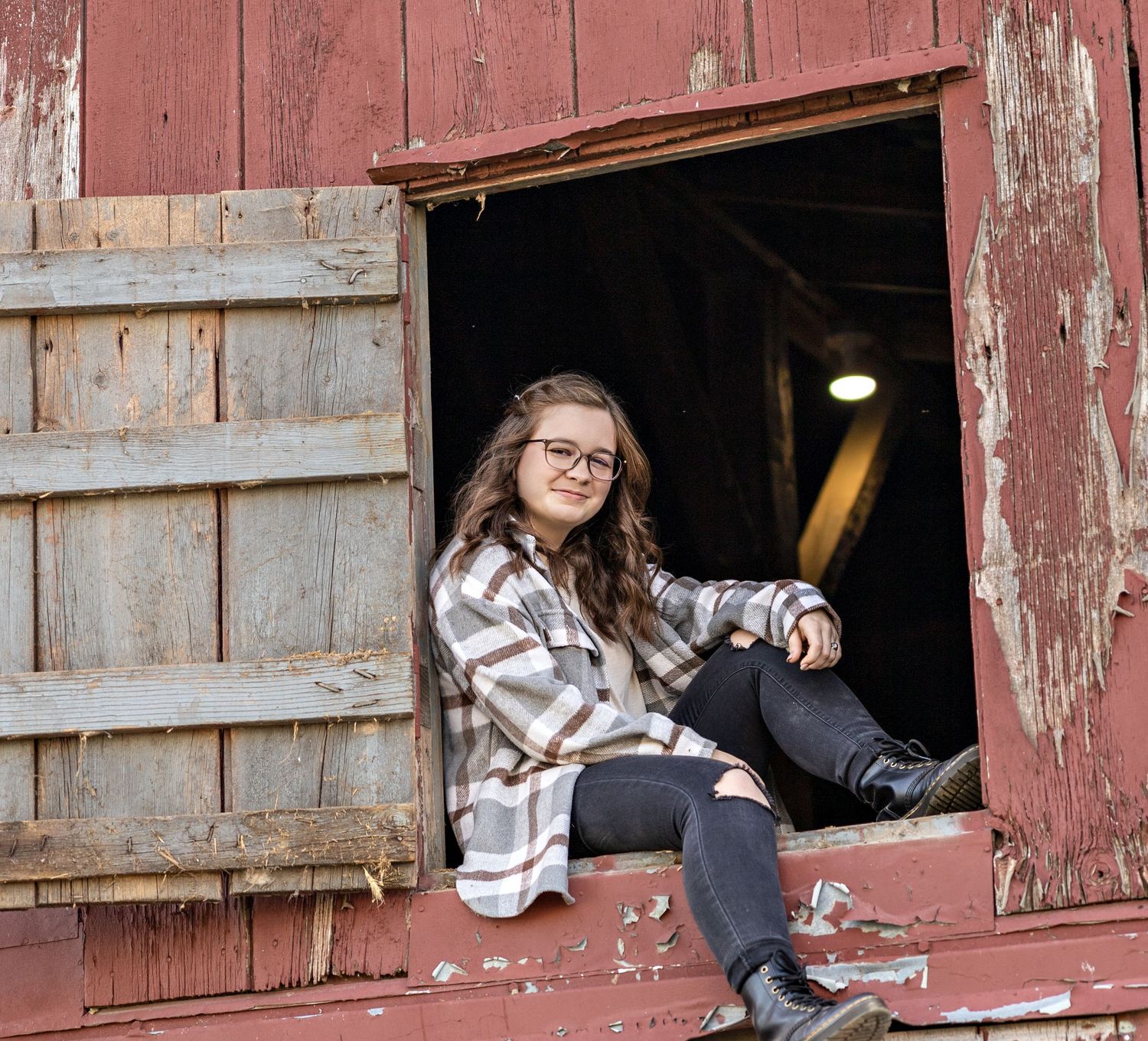 A rustic portrait taken through an old red barn window opening.
