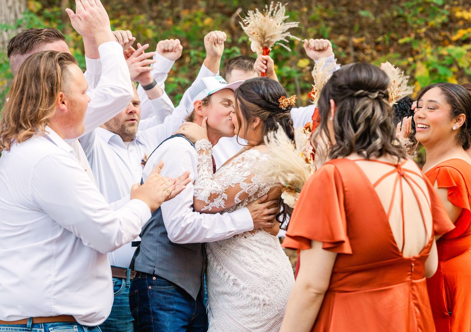 Wedding celebration with guests dancing and celebrating outdoors.
