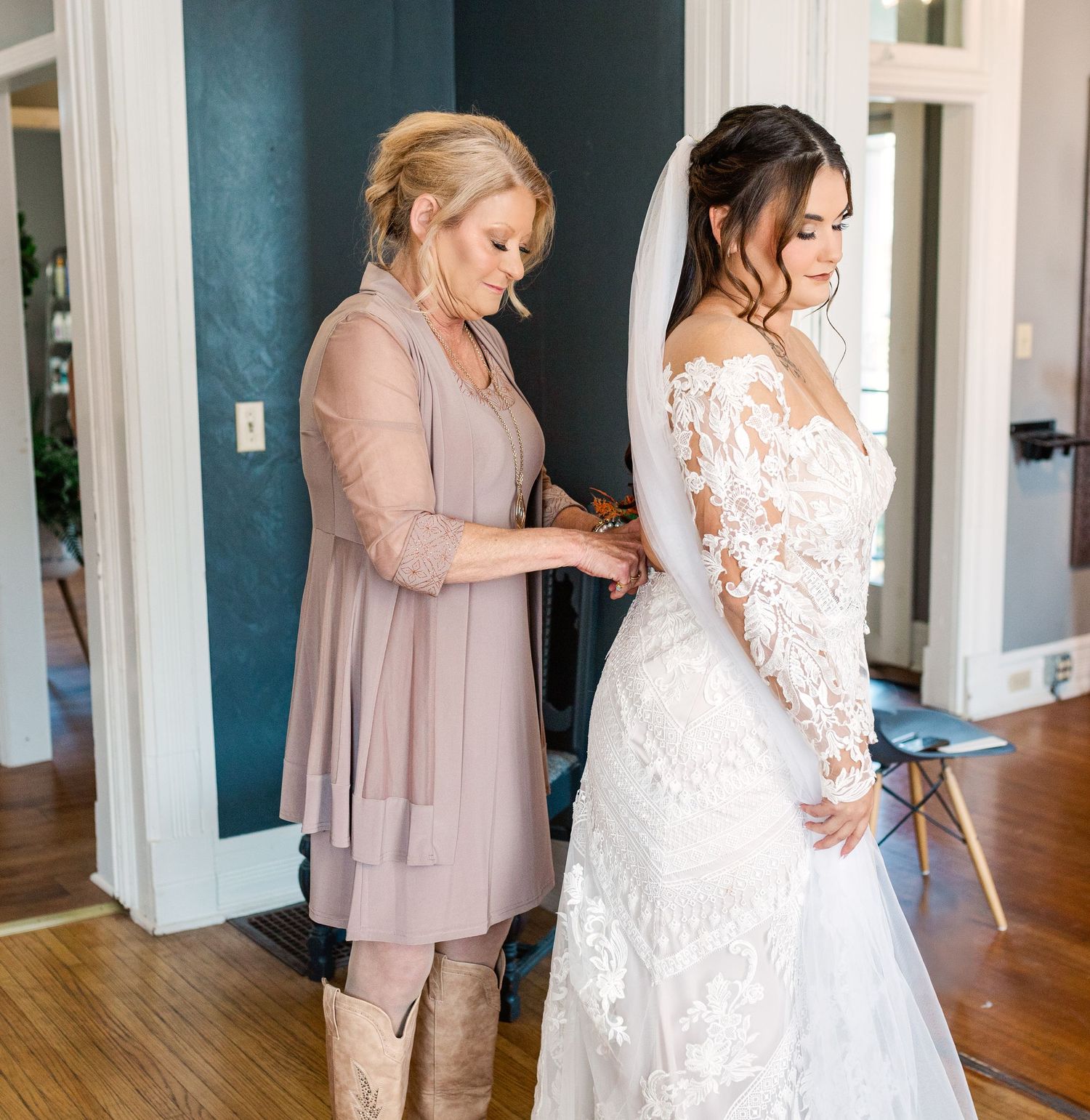 Final wedding dress preparations in a room with teal walls and hardwood floors.