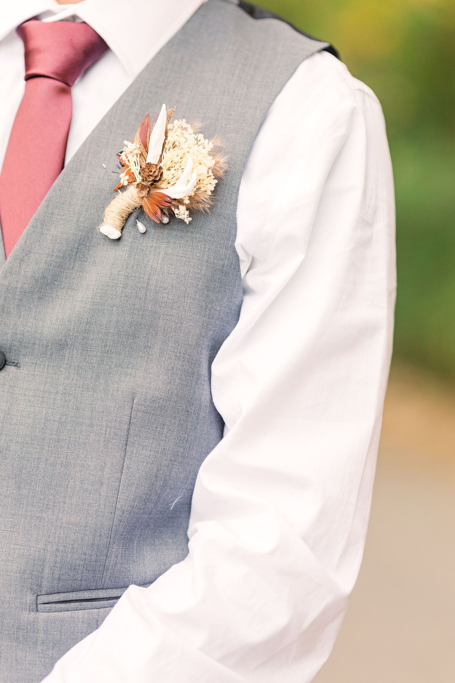 Gray vest with pink tie and dried flower boutonniere detail.