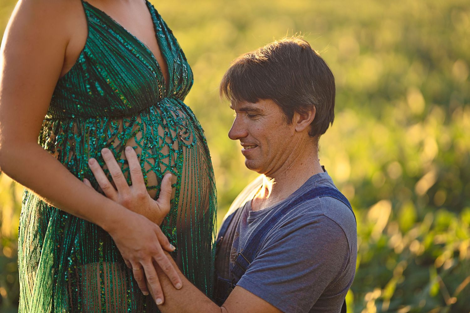 A tender maternity moment captured with a couple in natural lighting outdoors.