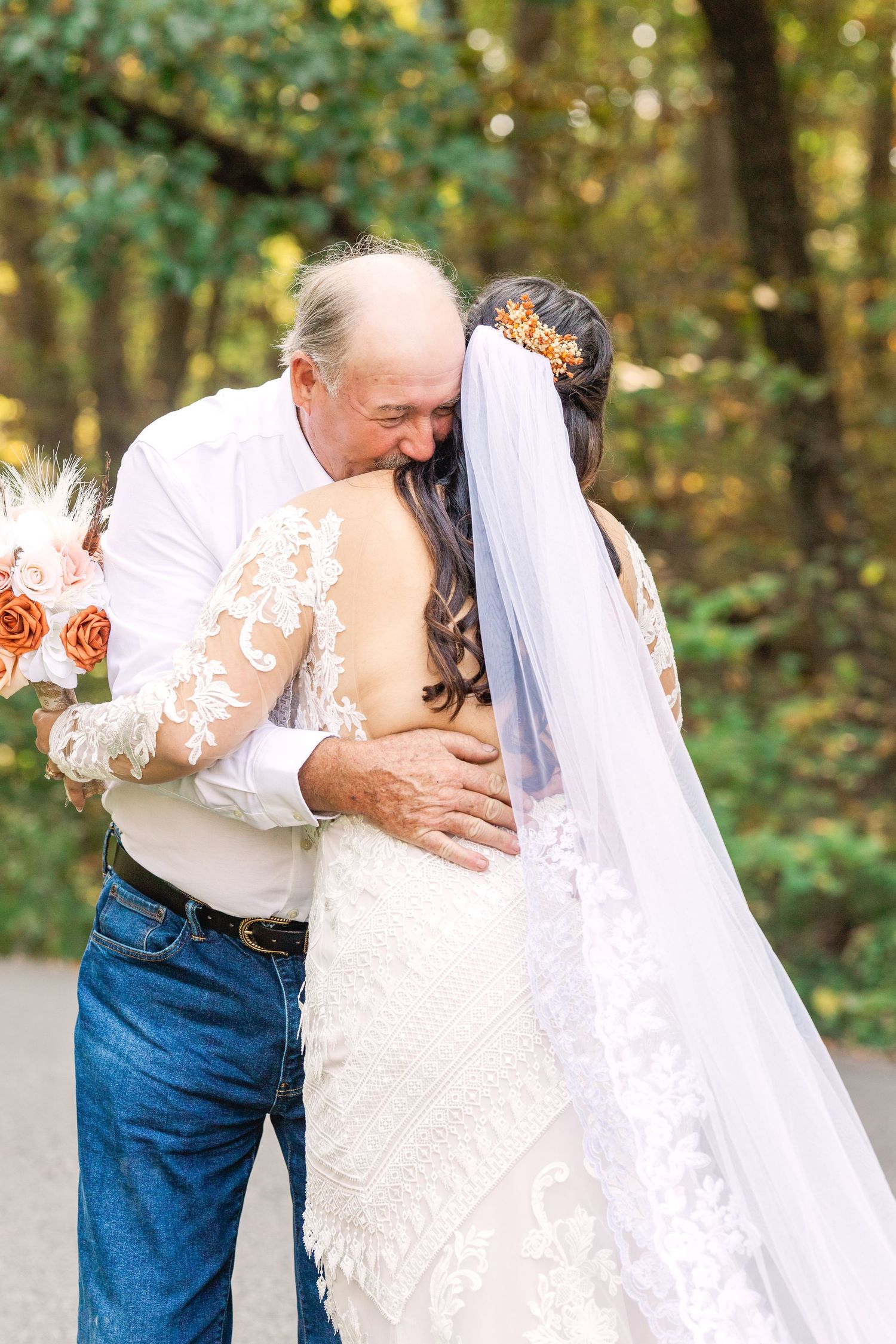 An emotional embrace between two people in a wooded setting during a wedding.
