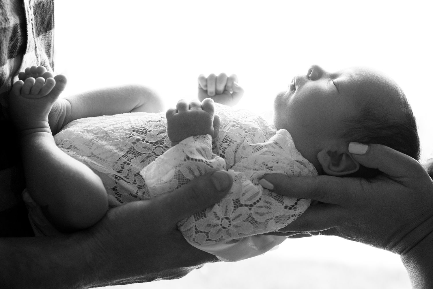 Seven black and white photos showing progressive stages of a newborn lying on a soft textured surface.