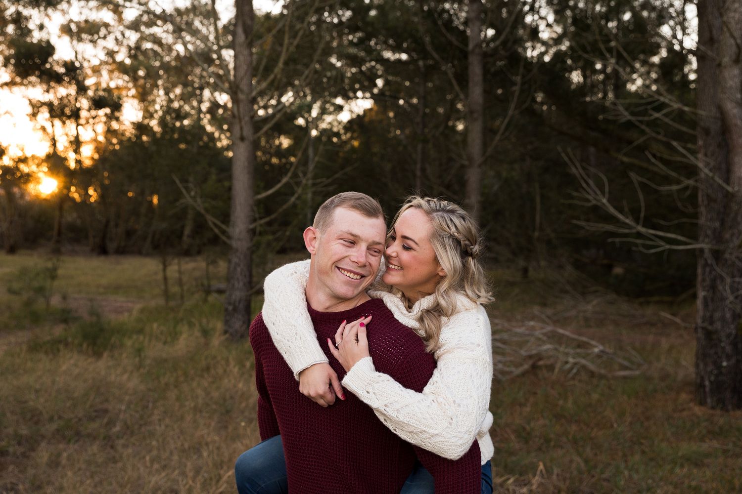 A cheerful couple shares tender moments while posing outdoors during golden hour.