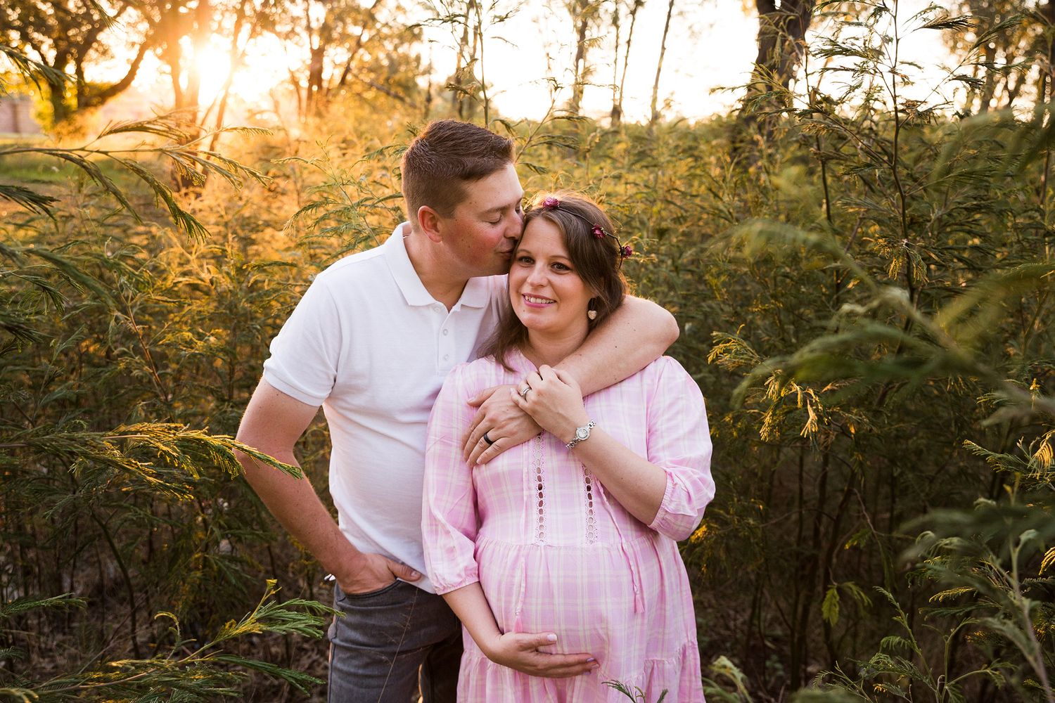 Golden sunset engagement photos in a wooded natural setting with soft lighting.