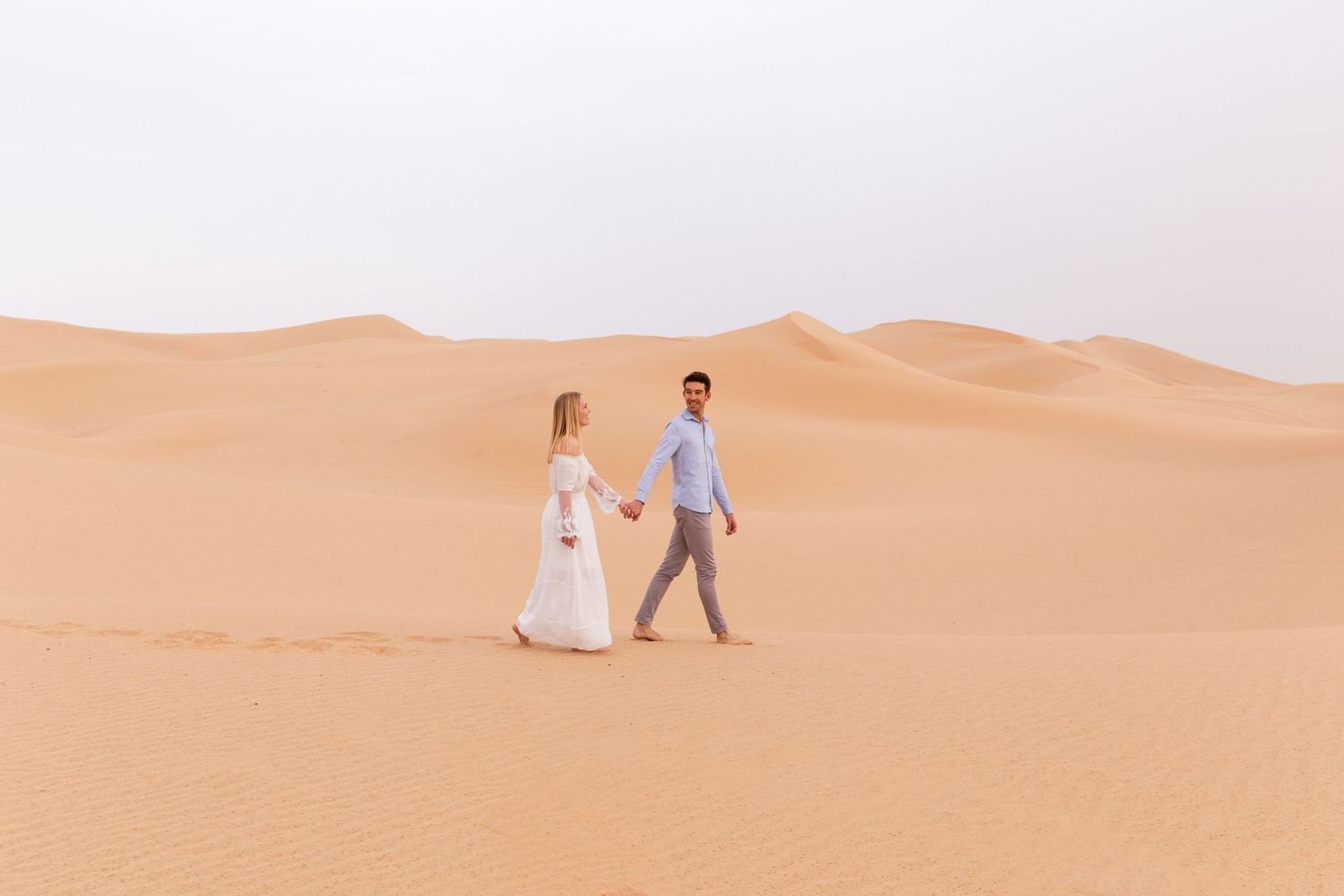 Minimalist desert wedding photos featuring soft sand dunes and clear sky.