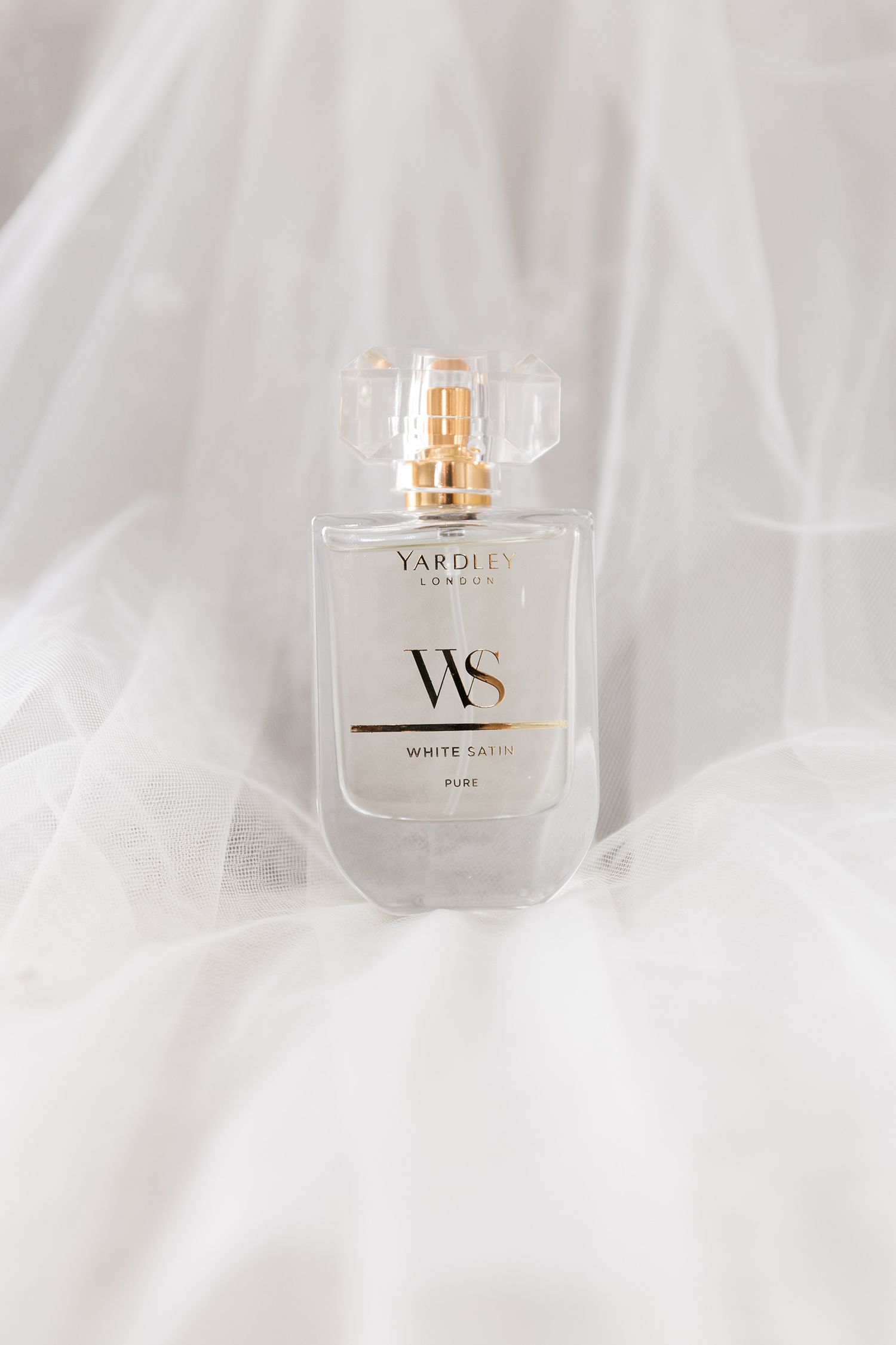 Luxury perfume bottle with 'VAPOURS' branding displayed on soft white fabric with elegant lighting and minimalist styling.