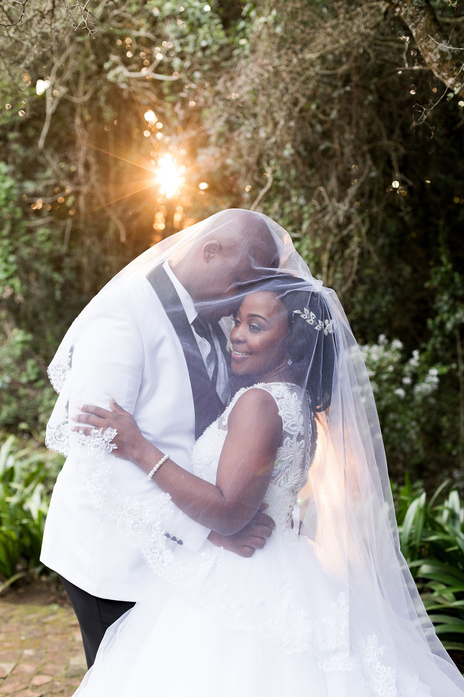 Romantic outdoor wedding series showing newlyweds embracing under natural sunlight and flowing white veil.