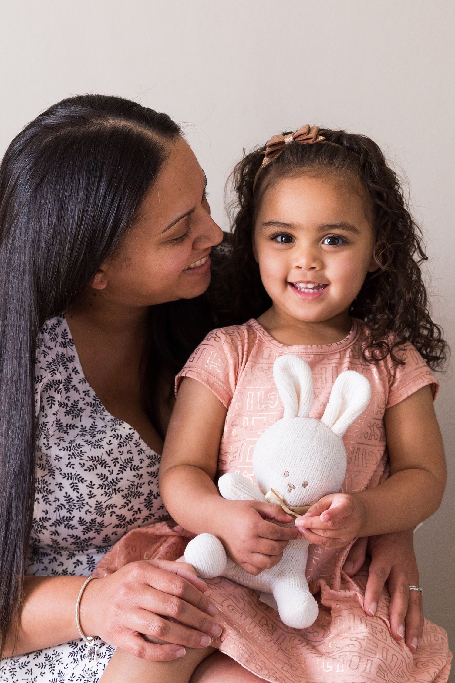 A heartwarming series of candid family moments captured in soft lighting while holding a white plush bunny toy.