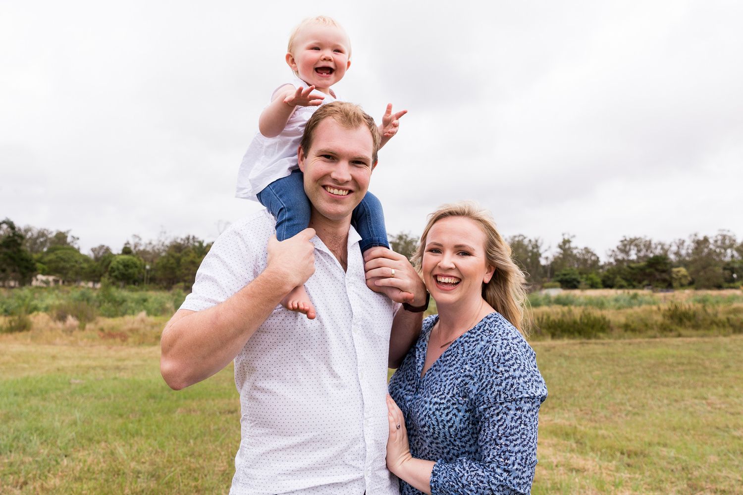 A happy group enjoying a casual outdoor photoshoot in a sunlit field on a bright summer day.