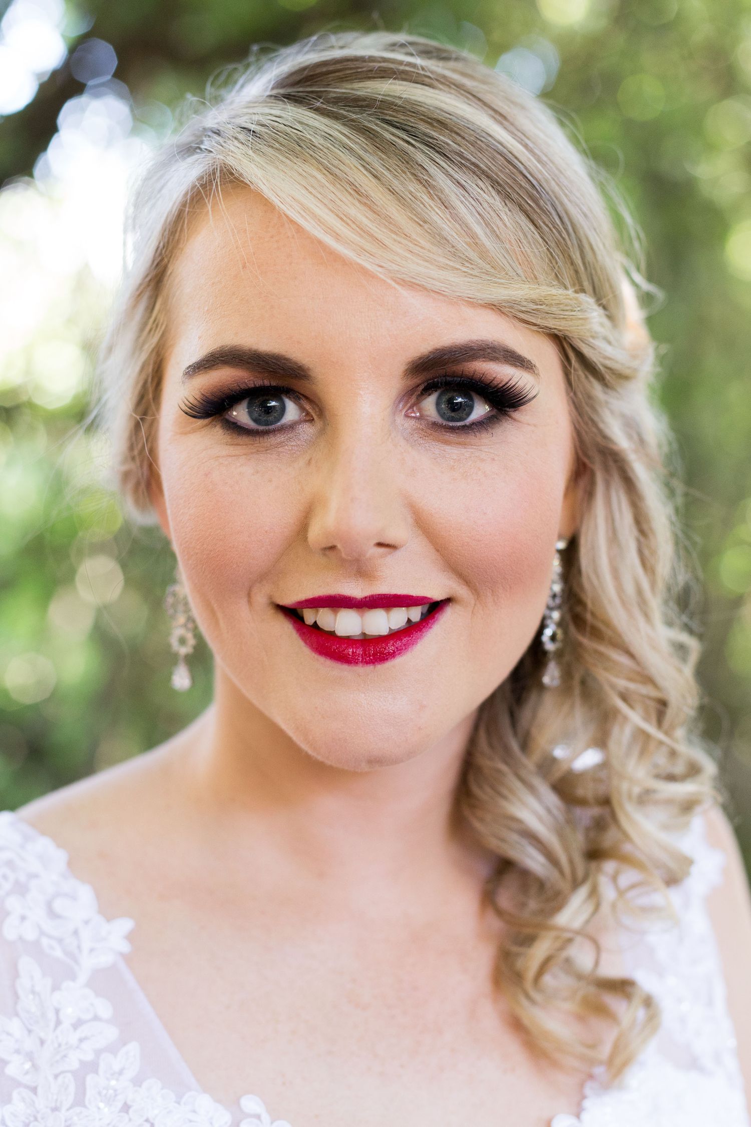 Detail closeup shots showing soft blonde curls, red lipstick and glamorous bridal makeup with blurred outdoor background.