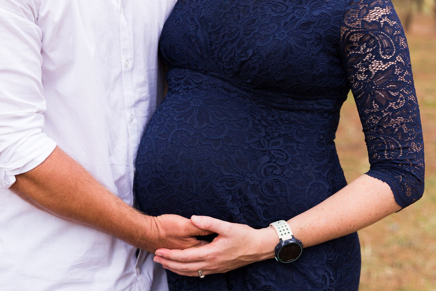 A couple in coordinated navy blue and white outfits embracing in an outdoor setting.