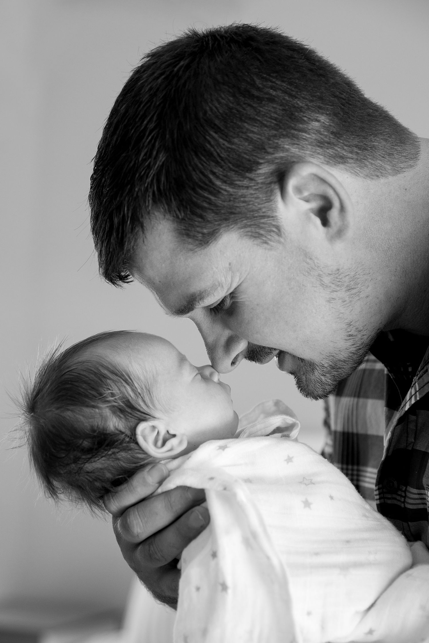 Professional black and white portrait series showing a tender embrace between a parent and infant in multiple angles.