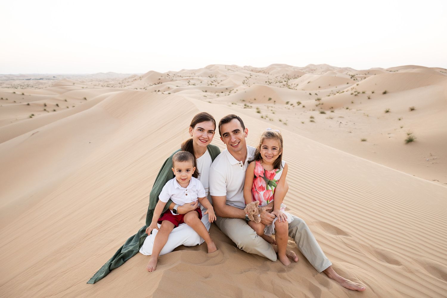 A scenic view of wind-swept sand dunes stretching across a vast desert landscape in warm golden sunlight.