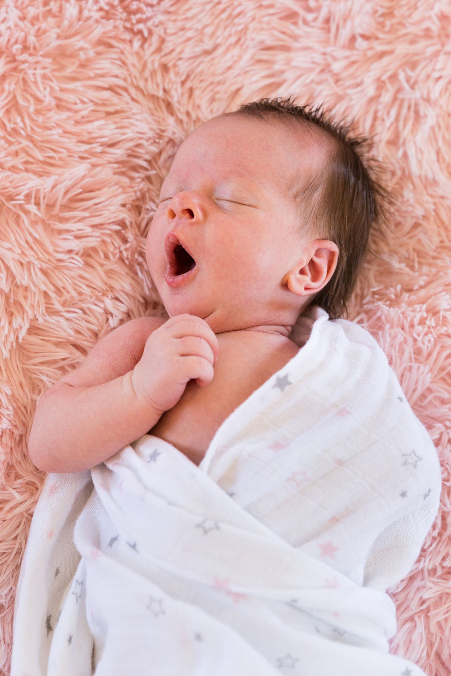 Sleeping baby in white onesie lying on soft pink fur blanket shown in five sequential photos.
