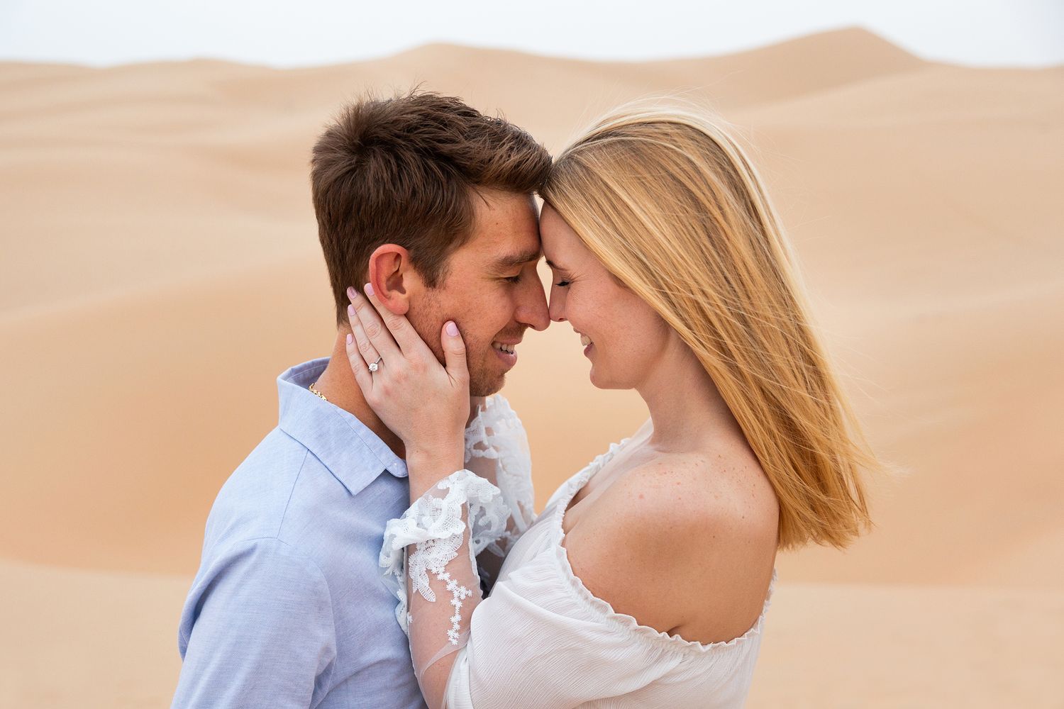 Couple sharing an intimate moment together in the sandy desert during sunset.