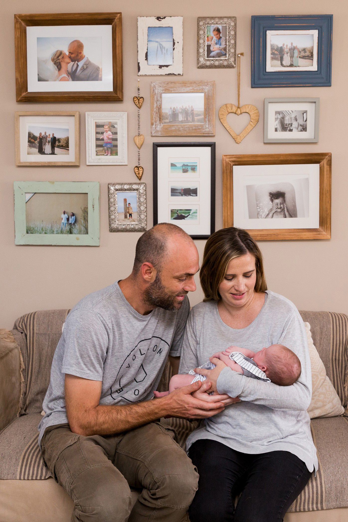 A collection of family photos arranged on a wall with various frames and heart decorations.
