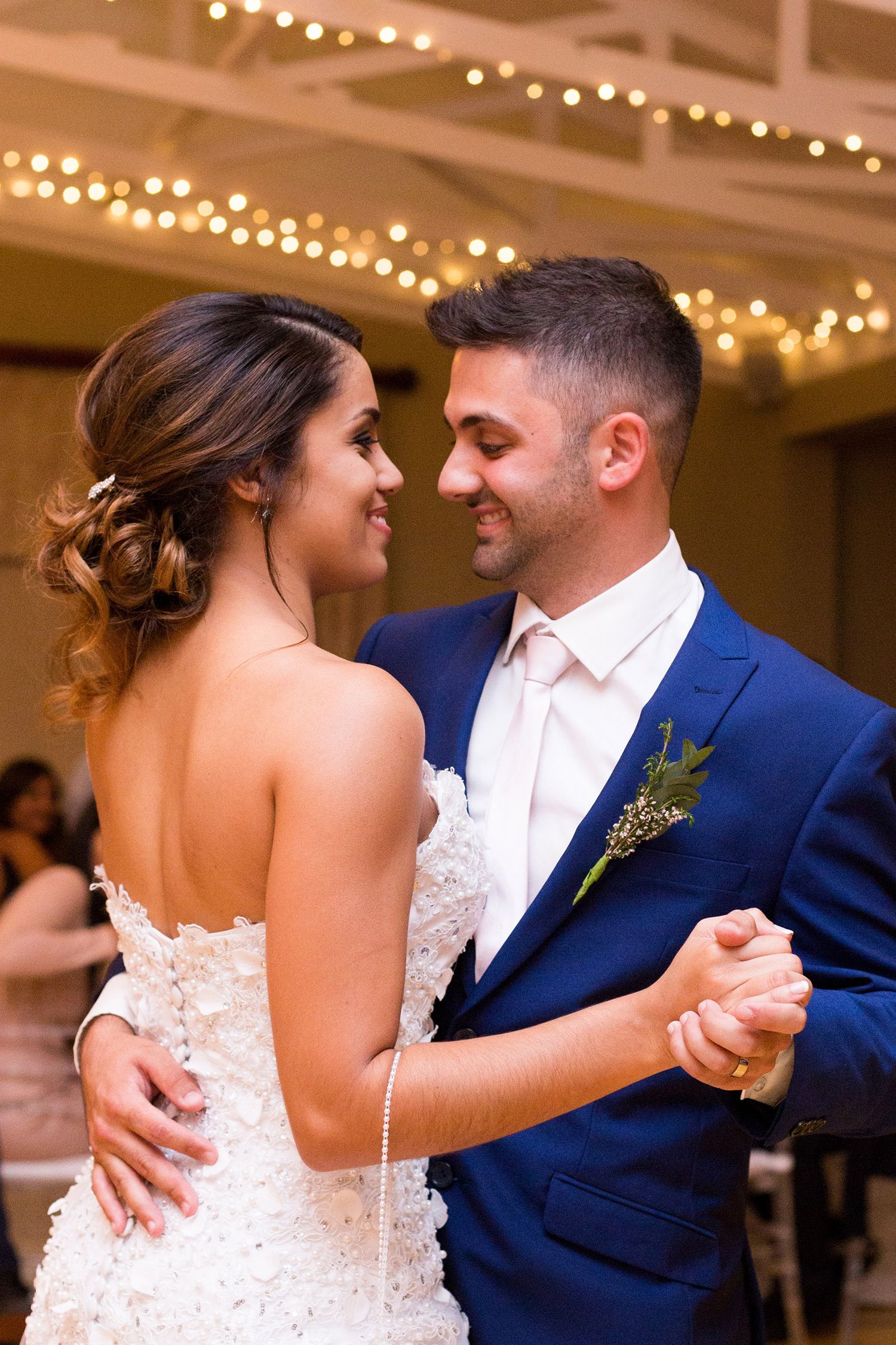 A romantic moment shared between newlyweds during their first dance at an indoor wedding reception.