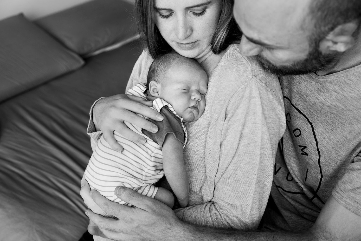 Black and white series of candid family moments showing tender bonding between parent and infant in cozy home setting.