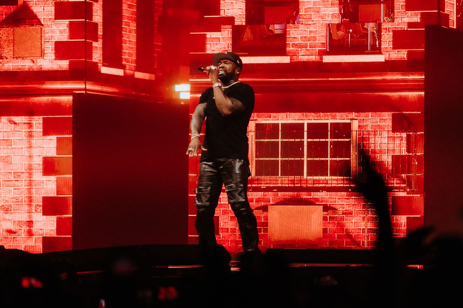 Rock band performs on stage with dramatic red lighting and dynamic movement during an energetic concert performance.