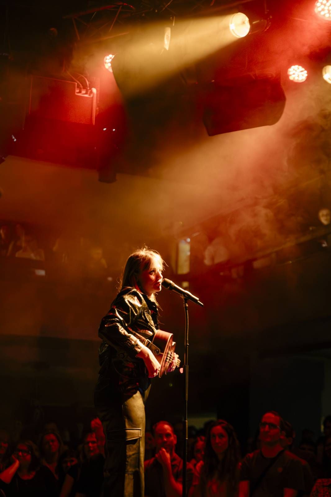 Silhouetted performer on stage bathed in dramatic red and gold lighting during a concert performance.