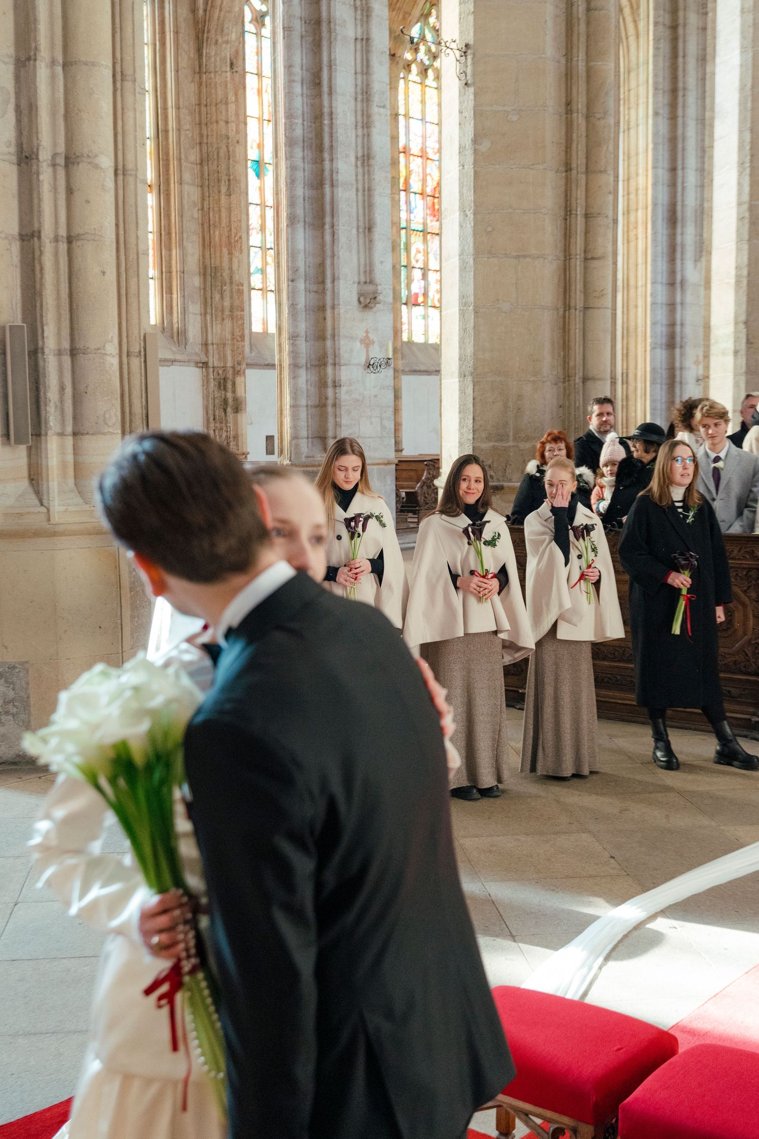 Wedding ceremony in a grand cathedral with stained glass windows and red carpet aisle.
