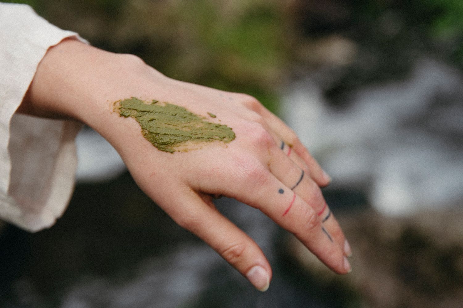 Series of hands with green material being applied in artistic fashion.