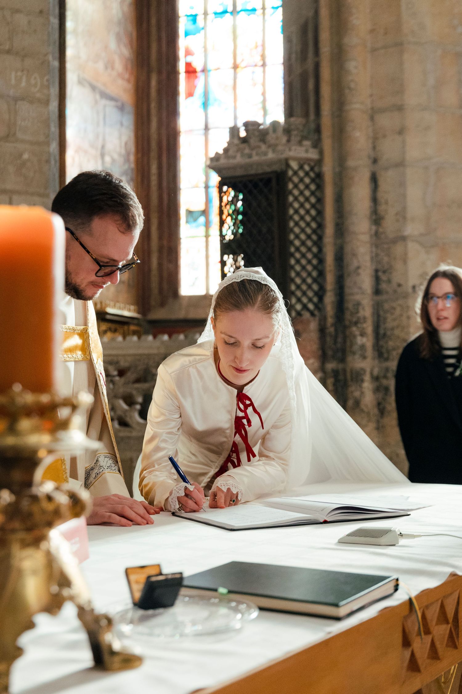 A wedding ceremony signing moment at an elegant church altar with candles and stained glass windows.