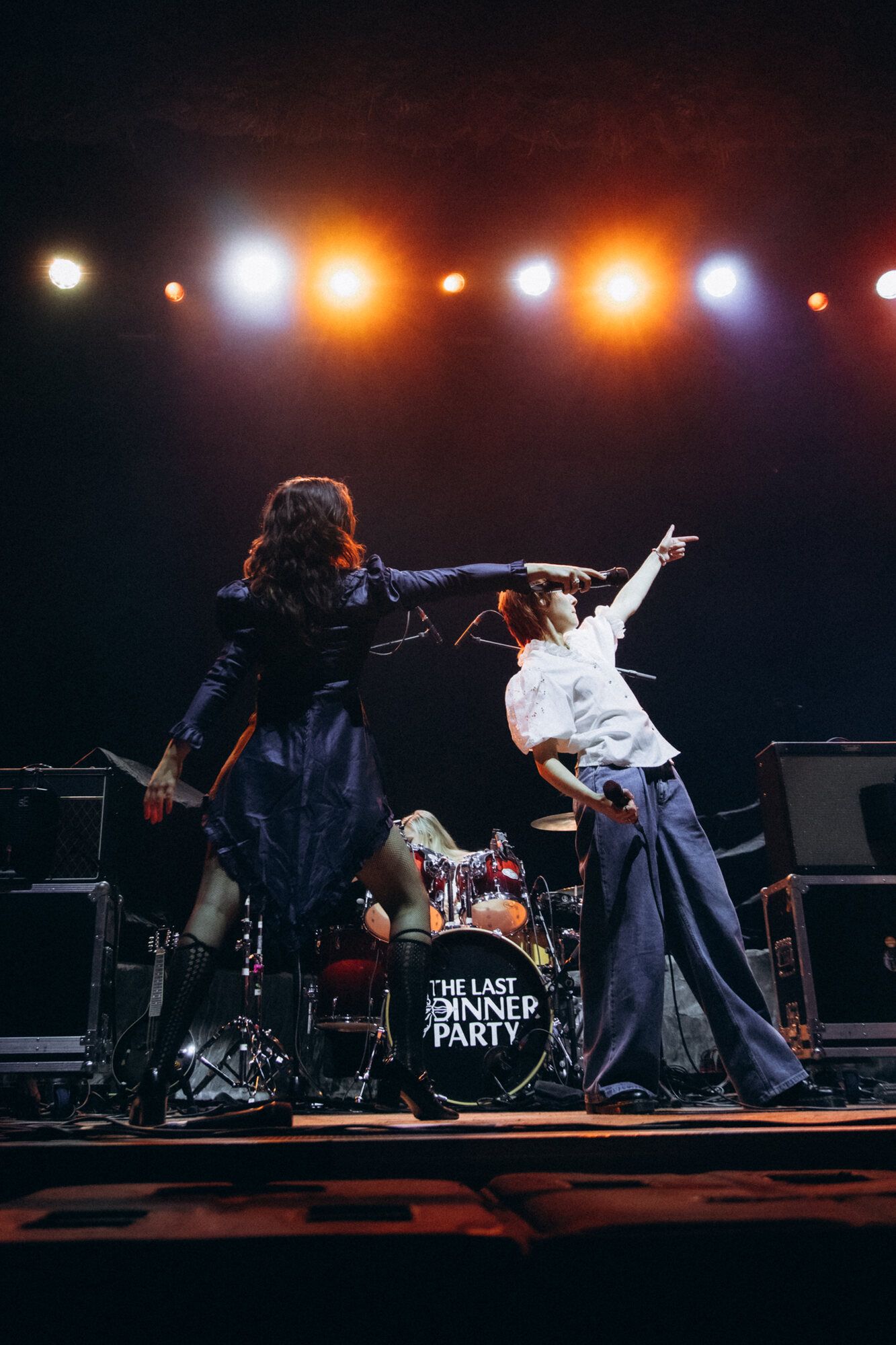 Band members silhouetted against stage lights perform an energetic rock show with dramatic poses.