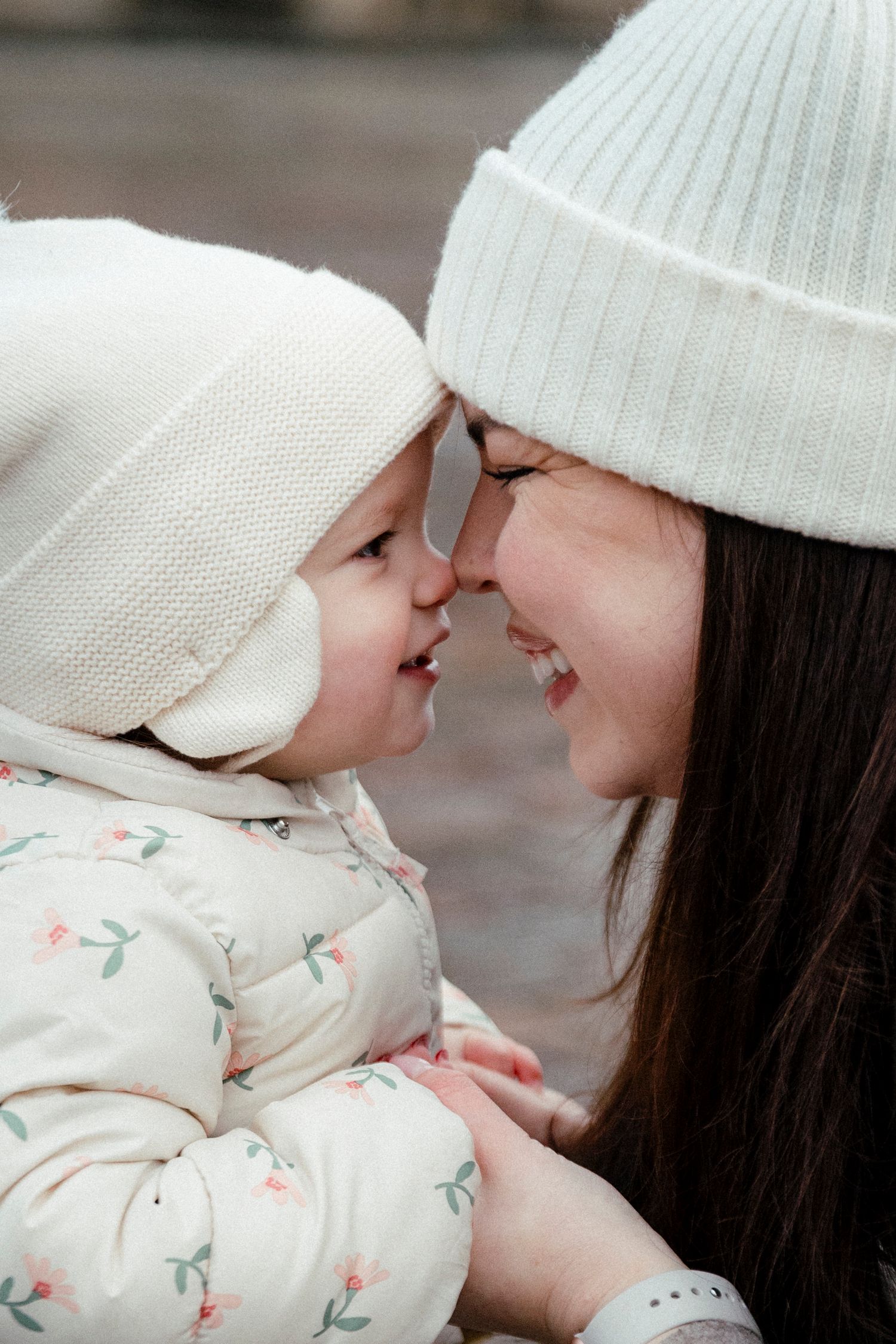 Tender moment between parent and baby wearing matching white winter hats.