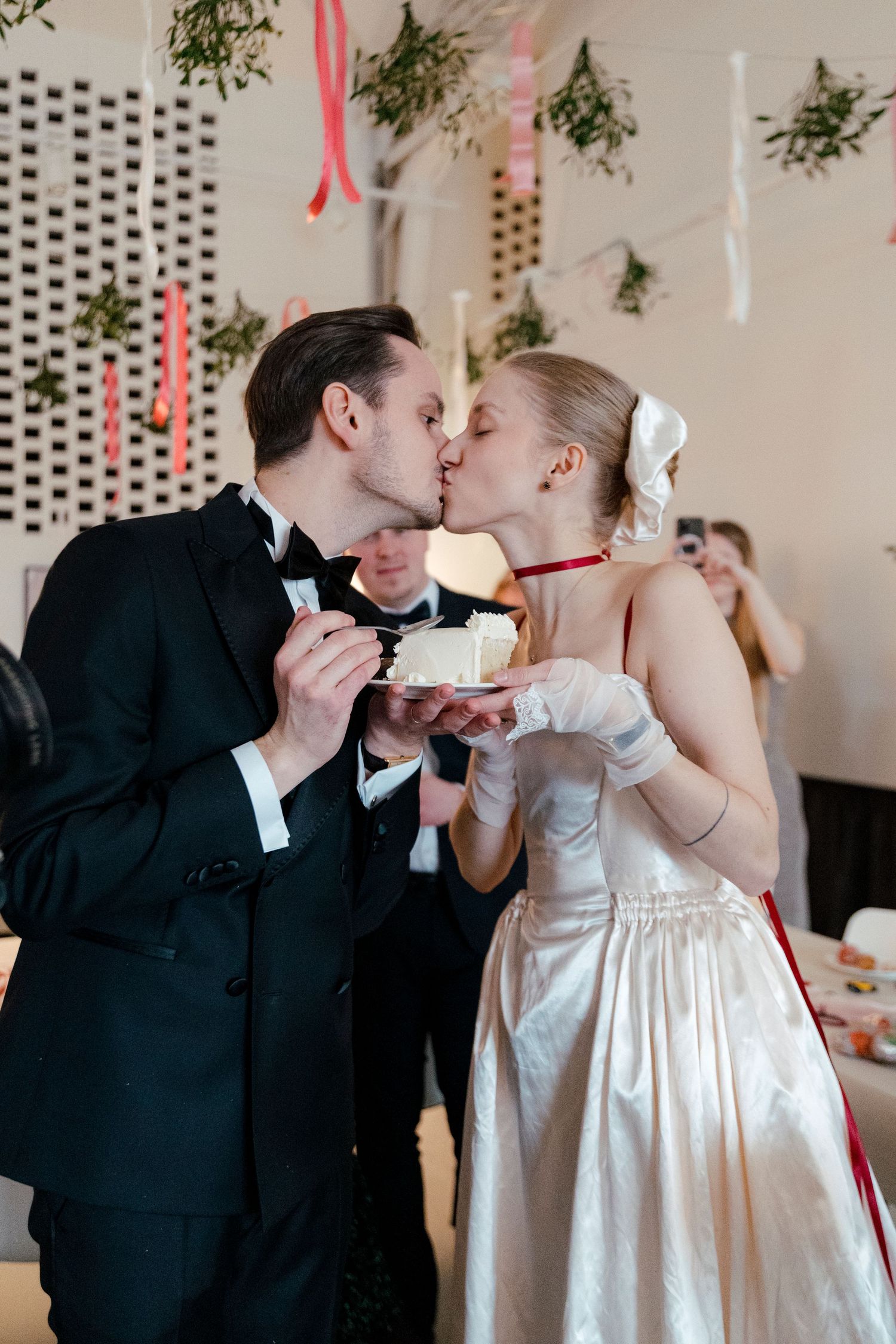 A couple in formal wedding attire share their first bite of cake together at their reception celebration.