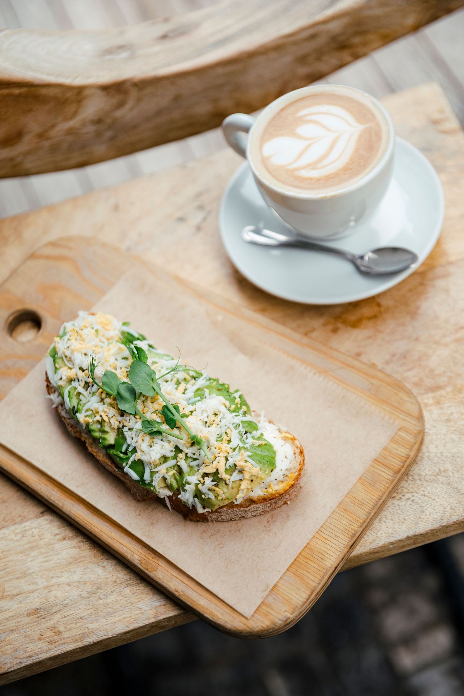 Artisanal sandwich and latte served on wooden board with rustic presentation.