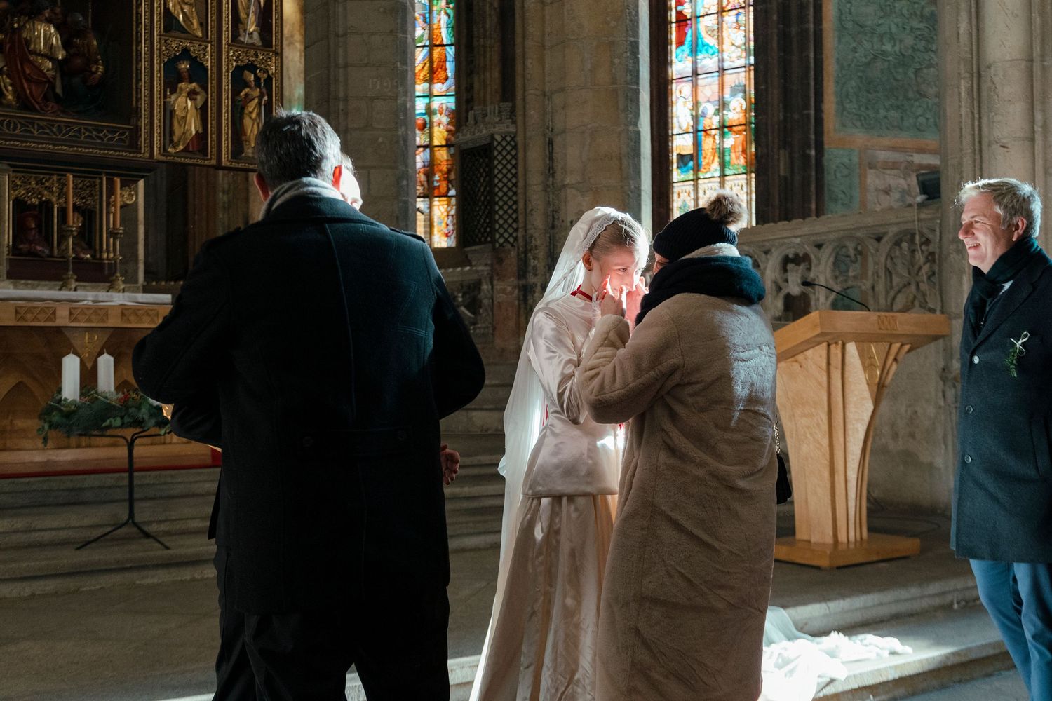 Wedding ceremony taking place in a grand cathedral with ornate stone architecture and stained glass windows.