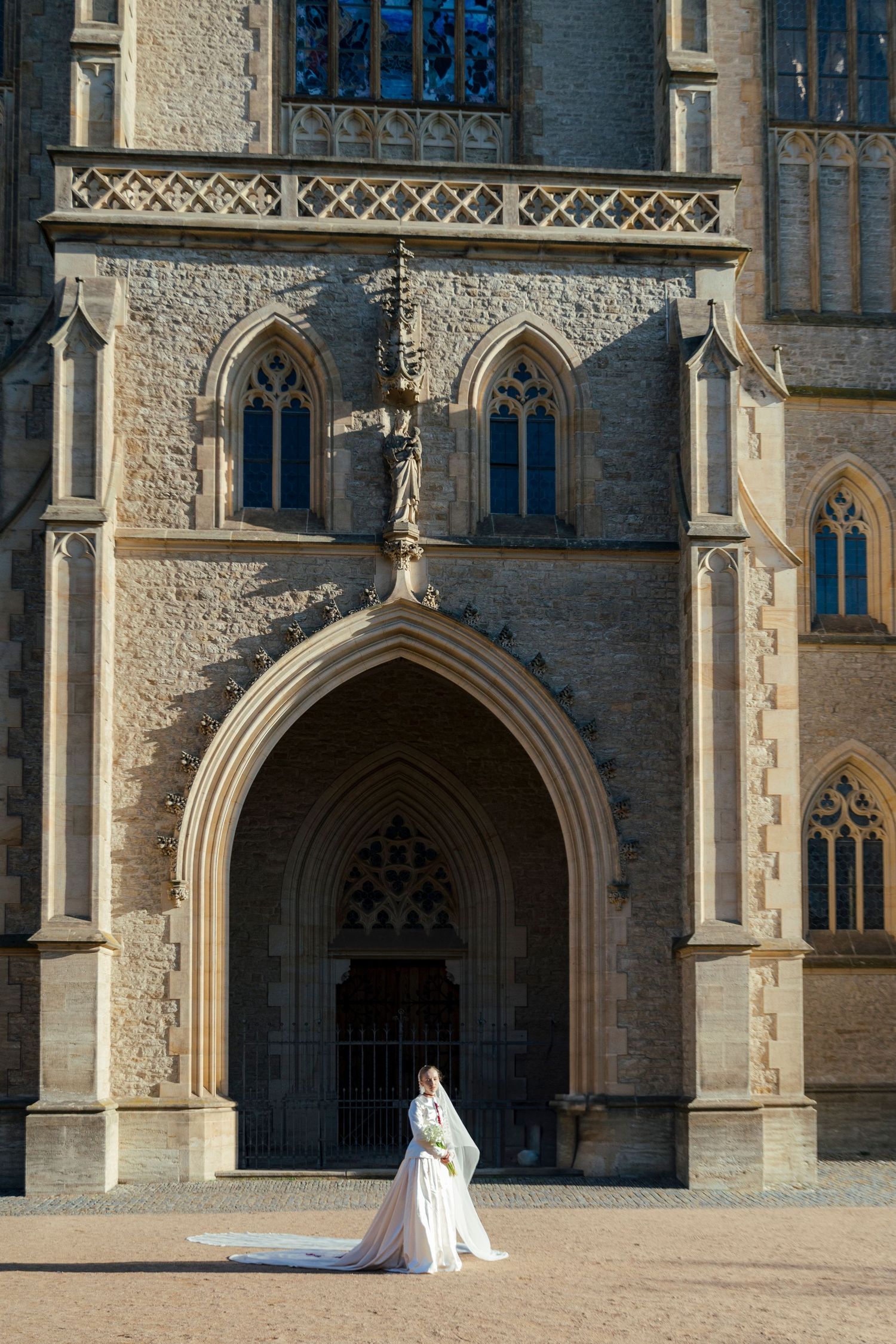 A wedding dress silhouette against a Gothic church entrance with pointed arches.