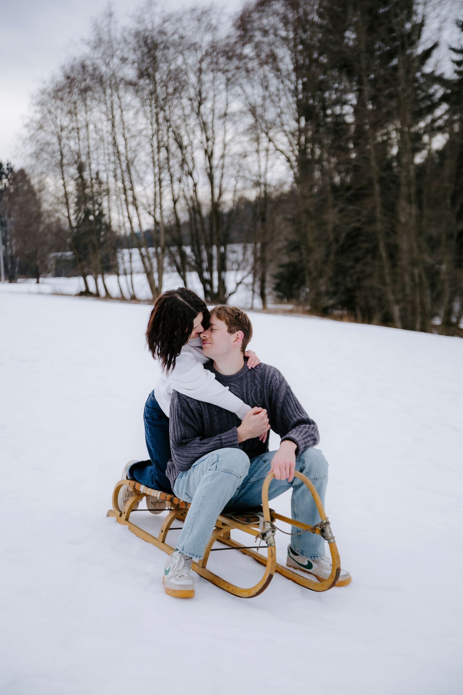 Two people share a playful moment while sledding in the snow.