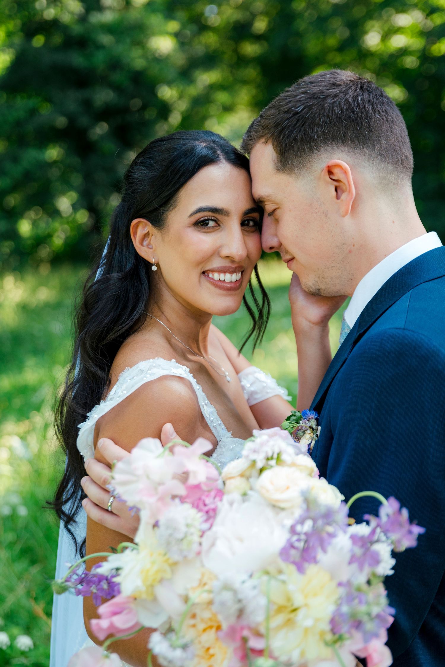 A romantic wedding moment captured outdoors with a beautiful bouquet of pink and white flowers.