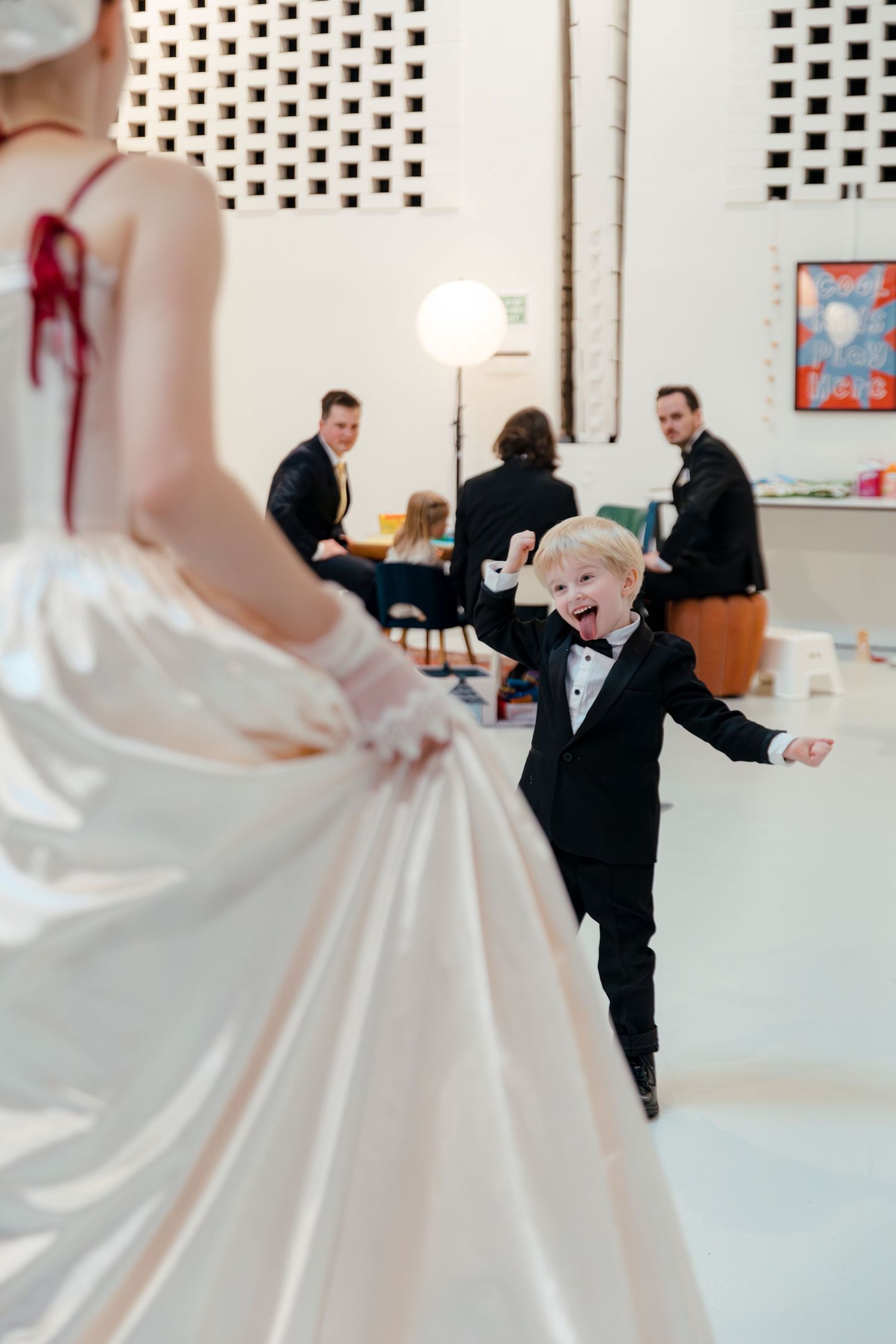Wedding guests dance and celebrate in a modern white room with decorative wall patterns.