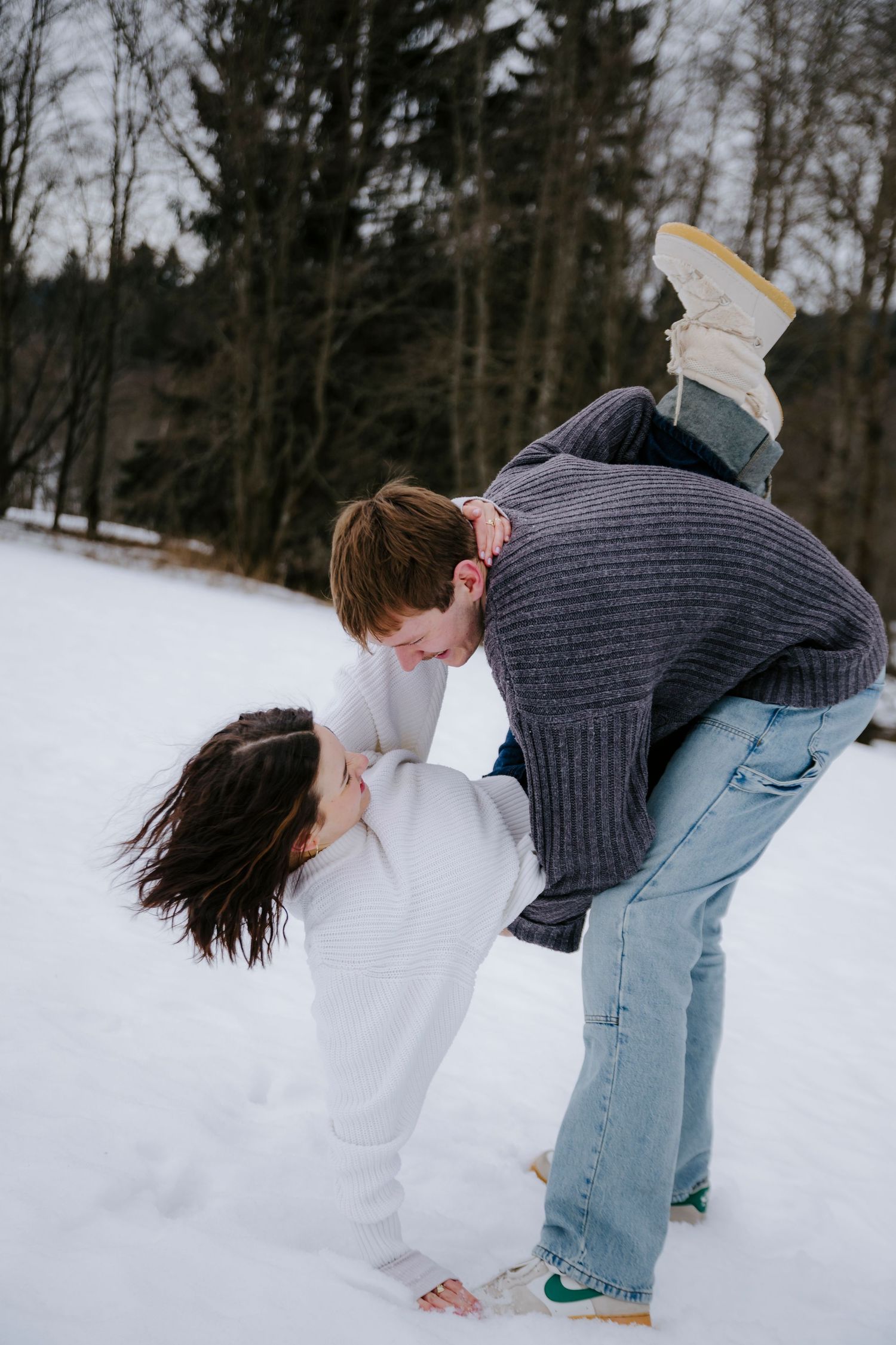 Couple playing and laughing together in the snow during winter.