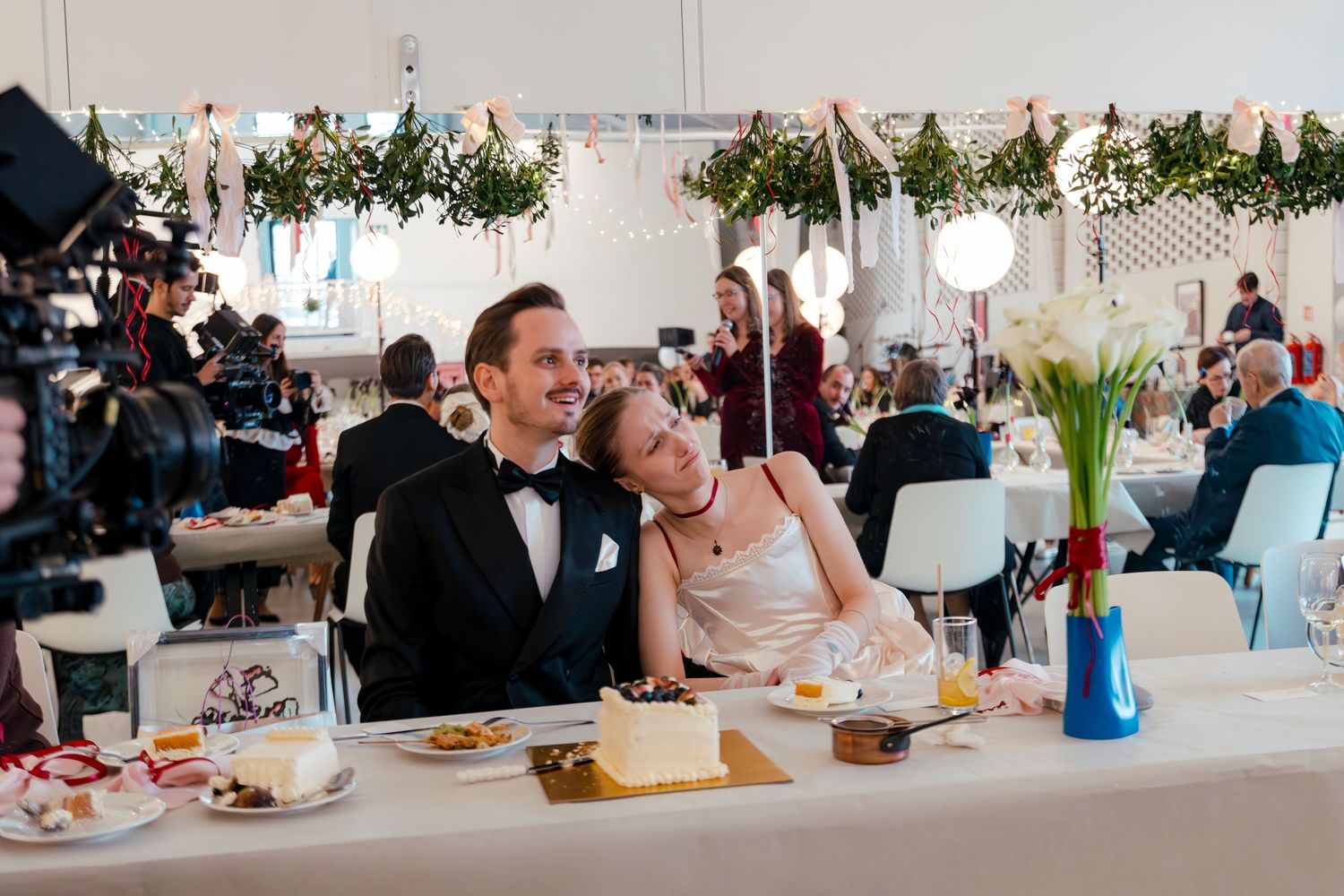 Elegant wedding reception tables decorated with white linens and floral centerpieces in a bright indoor venue.