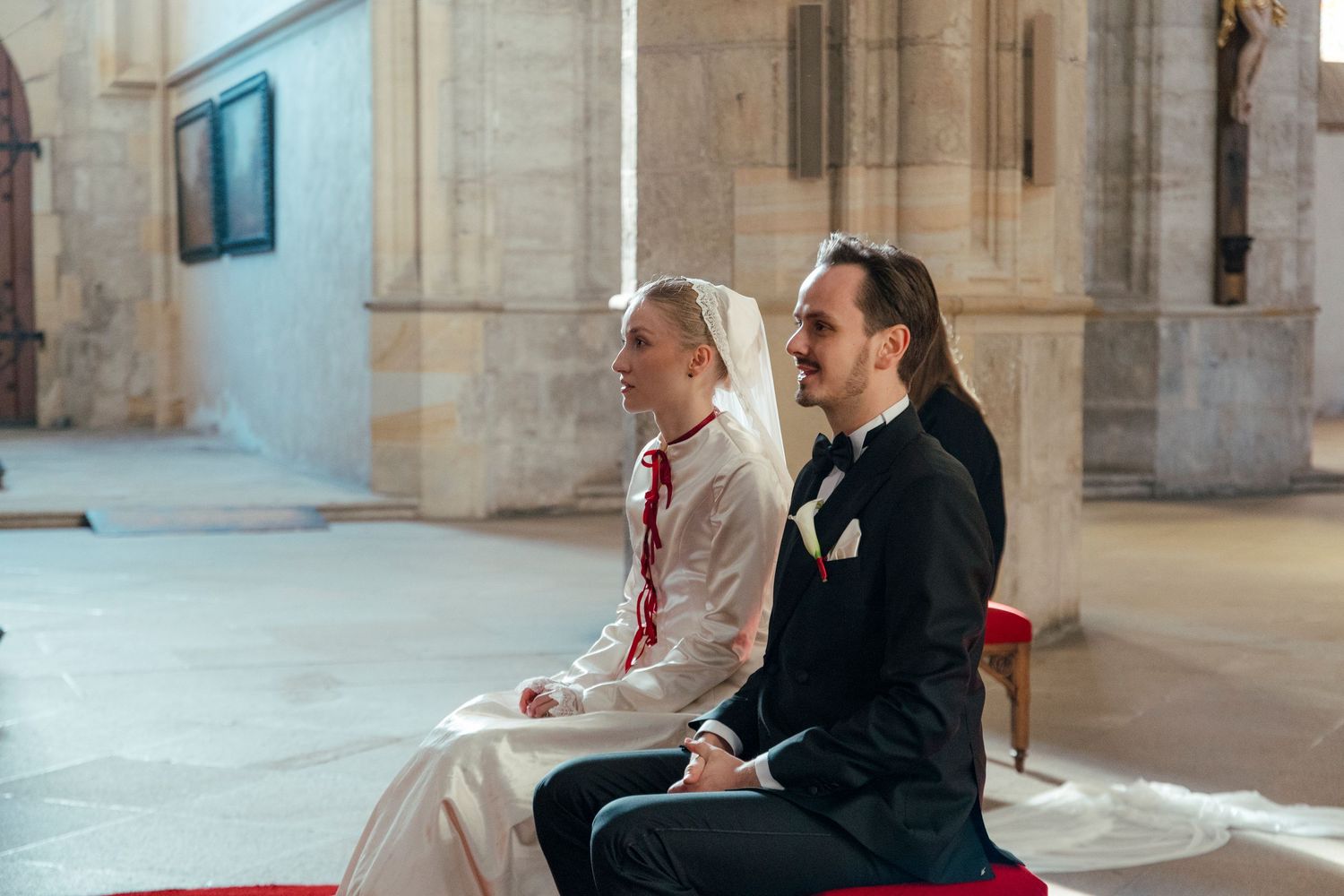 Wedding attendees seated in wooden pews inside a historic stone church with vaulted ceilings.