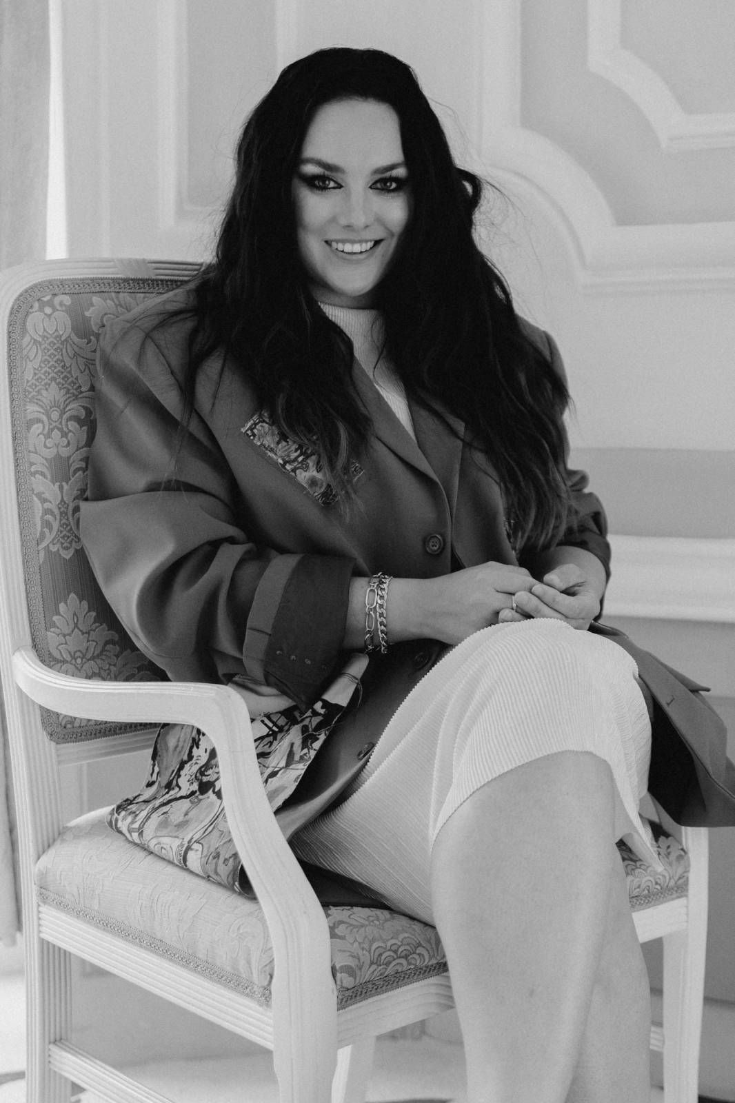 A black and white photo series shows someone in dark clothing lounging on a white chair in different relaxed poses.