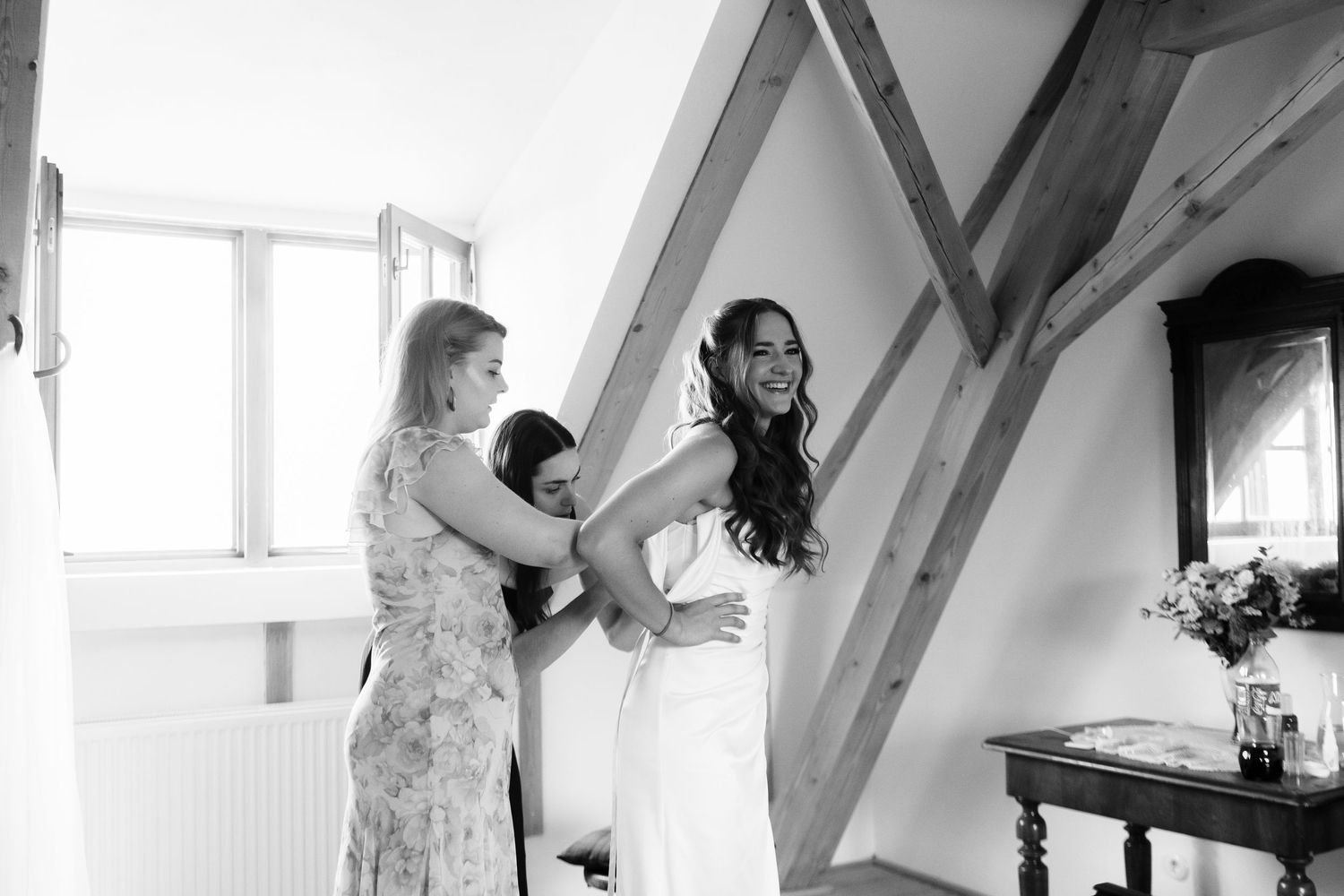 Black and white getting ready moments in an attic room with natural light.