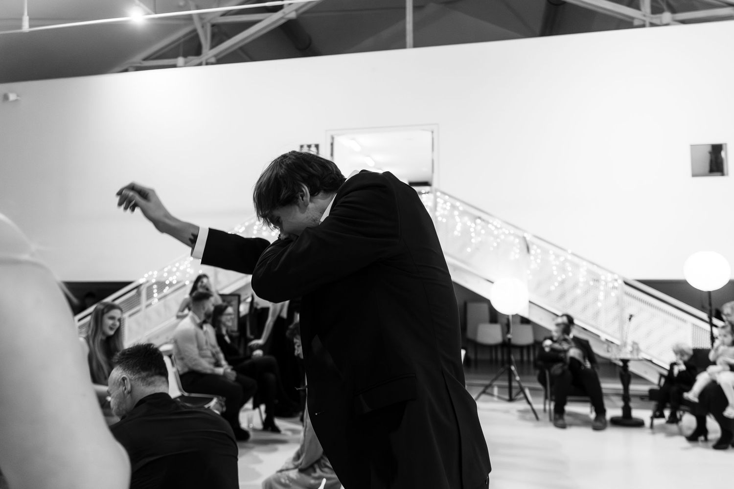 Black and white photo of dancers practicing in a dance studio with high ceilings and natural lighting.