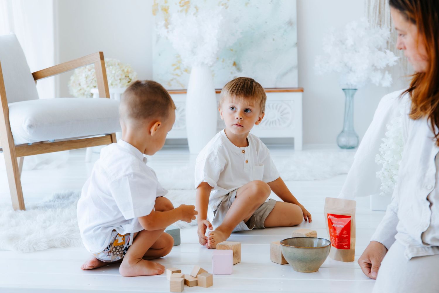Children in white clothing baking together in bright kitchen setting.