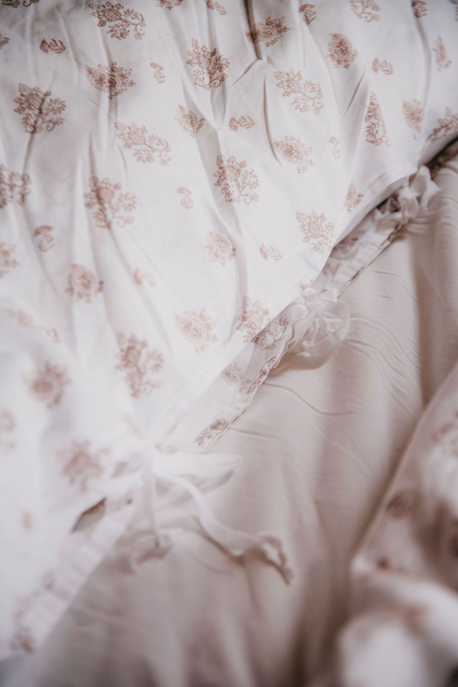Delicate white fabric with subtle floral pattern in soft focus.