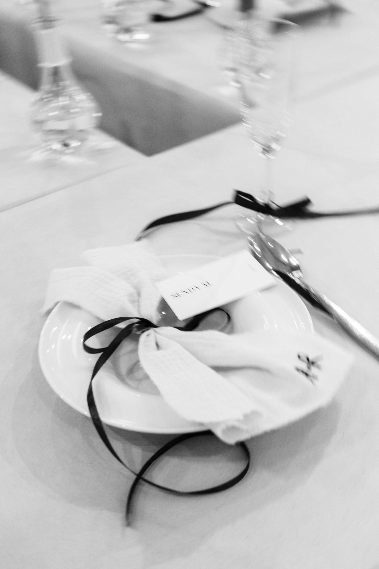 Elegant white place settings with black ribbon accents create a minimalist table decoration in monochromatic style.