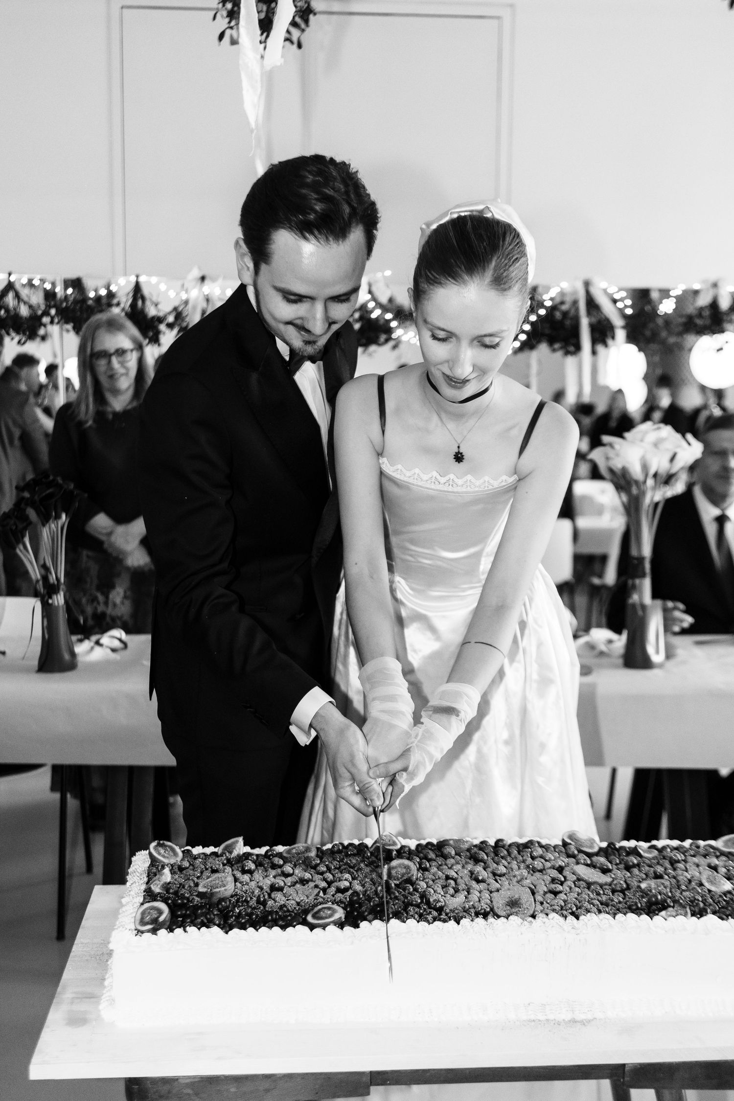 Newlyweds cut into a unique dessert display at their wedding reception, working together to serve their guests.