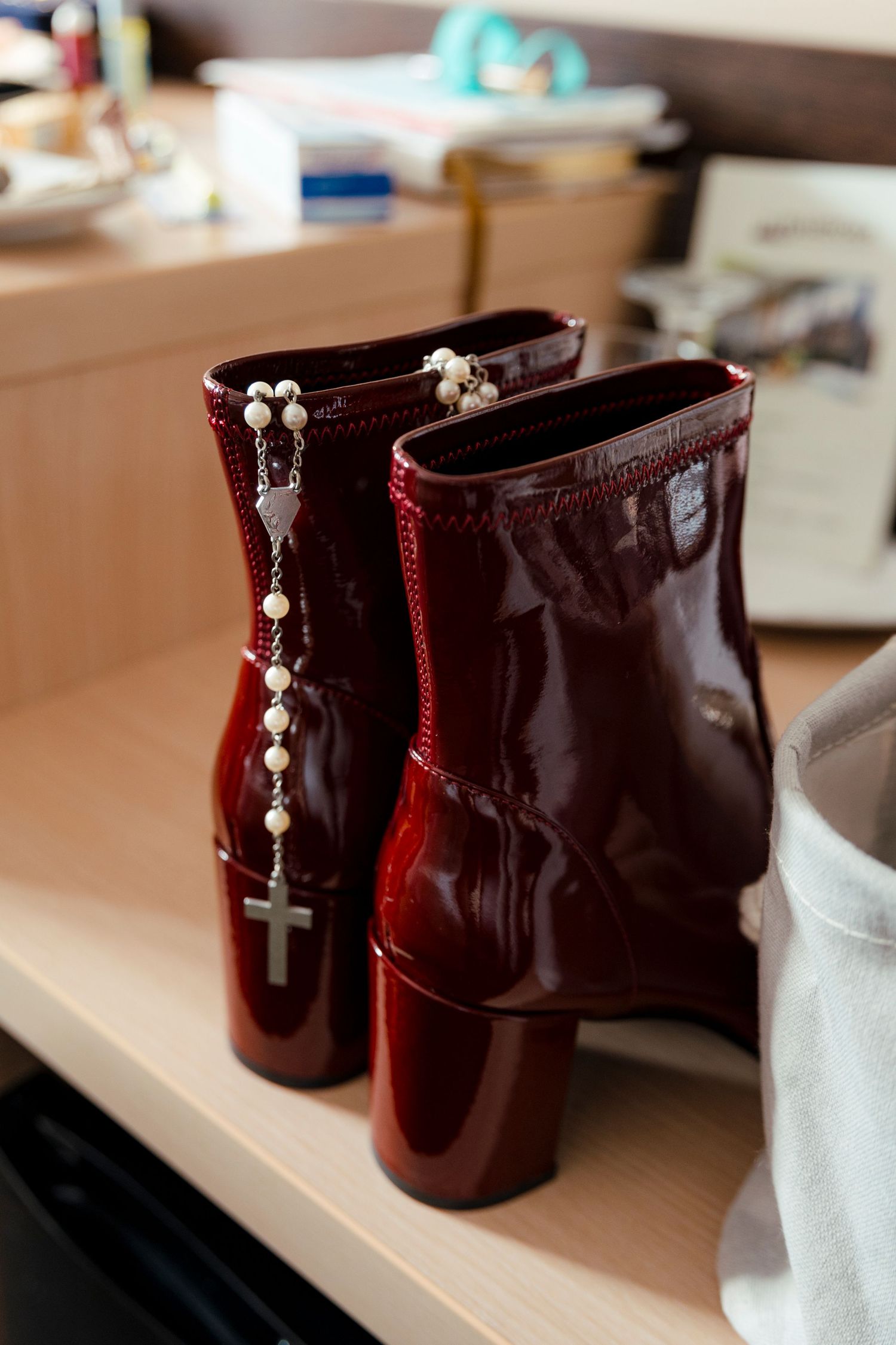 Burgundy patent leather boots with decorative cross charms on display.