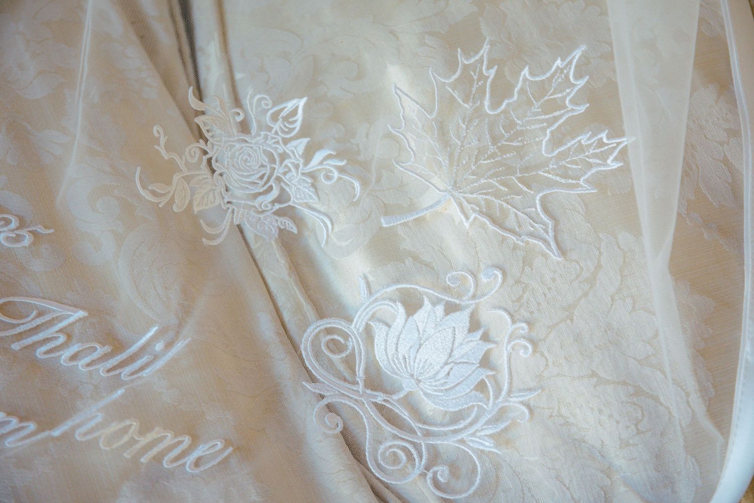 Close-up of delicate white maple leaf embroidery on fabric.